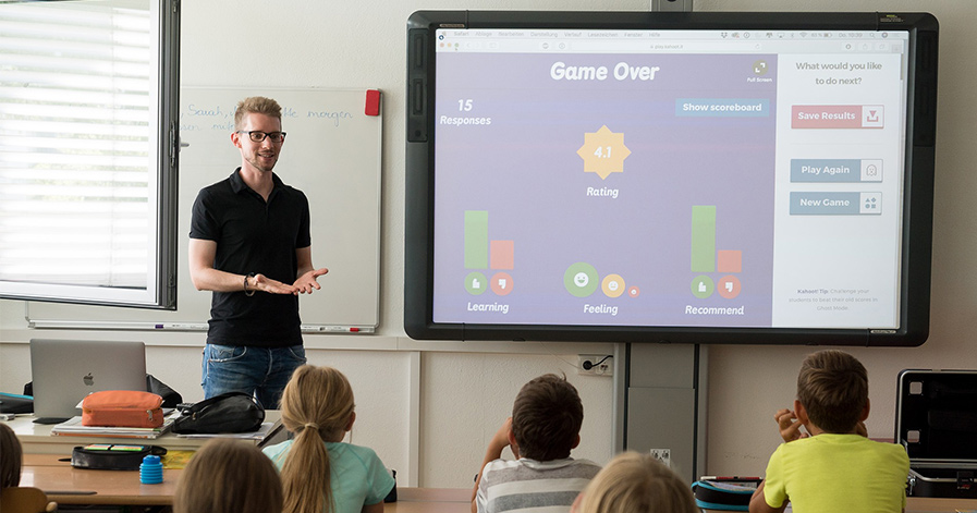 Teacher at a smart board at front of a classroom full of kids