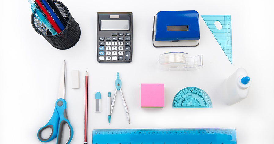 School supplies such as pencil sharpener, calculator, protractor on table