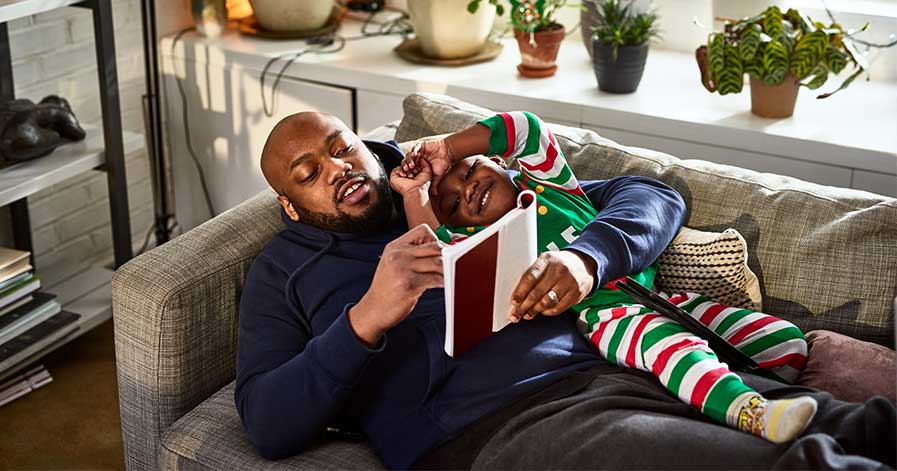 a father reading with his young son on the couch