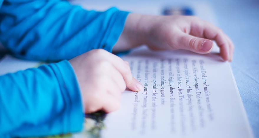 A child pointing to the words in a book as they read.
